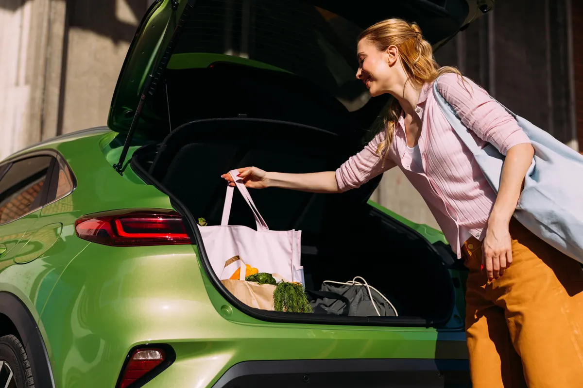 A woman unloading shopping bags from the boot of a car